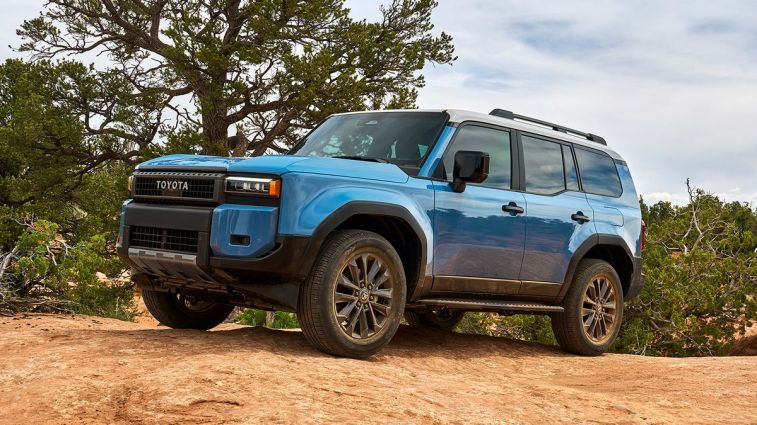 2024 Toyota Land Cruiser in blue on flat rock with trees in background.