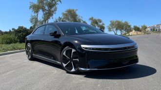 2023 Lucid Air Pure in black with trees in the background.