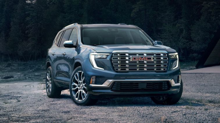 2024 GMC Acadia Denali in blue near a forest.