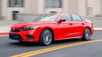 2024 Honda Civic Sedan in red driving on a road.