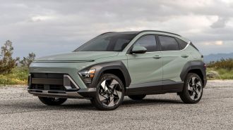 2024 Hyundai Kona Limited in green with clouds in the background.
