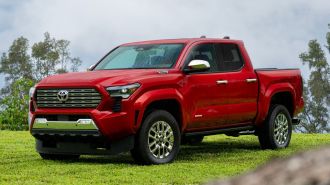 2024 Toyota Tacoma Limited in red on a grassy area.