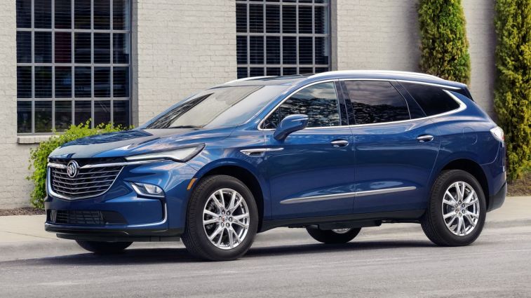 A 2024 Buick Enclave in blue parked next to the building.