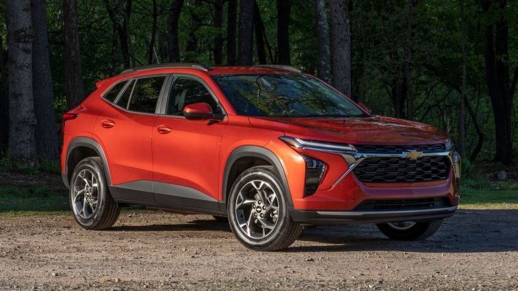 2024 Chevrolet Trax LT in Cayenne Orange Metallic parked on a gravel road in front of trees.