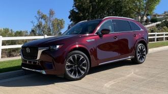 2024 Mazda CX-90 Turbo in Artisan Red near a white fence.