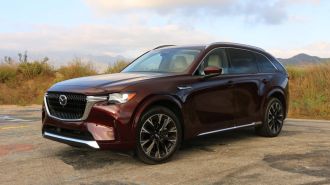 2024 Mazda CX-90 in Artisan Red Metallic with clouds in the background.