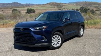 2024 Toyota Grand Highlander Hybrid in blue with hills in the background.