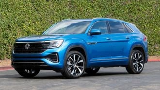2024 Volkswagen Atlas Cross Sport in blue with greenery in the background.