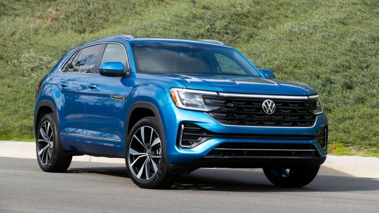 2024 Volkswagen Atlas Cross Sport in blue with greenery in the background.