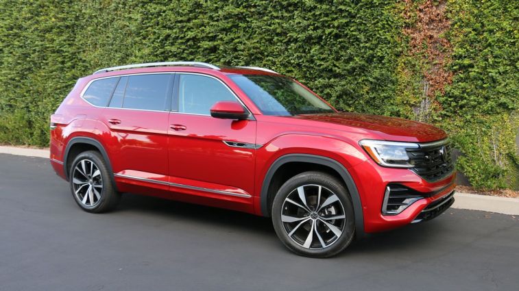 2024 Volkswagen Atlas SEL in red near a green ivy wall.
