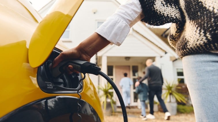 A person plugging home charging station into car