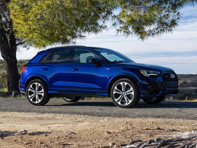 2023 Audi Q3 S Line in blue next to a tree.