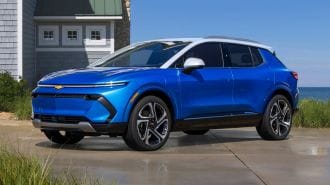 2024 Chevrolet Equinox EV 3LT in Riptide Blue parked beside a lakeside home.