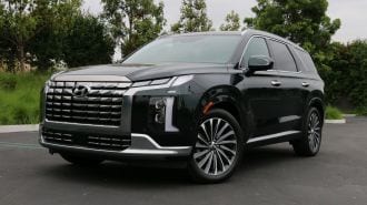 2024 Hyundai Palisade in emerald green near grass and trees.