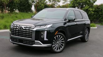 2024 Hyundai Palisade in emerald green near grass and trees.