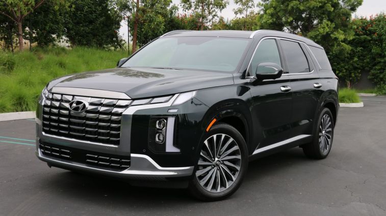 2024 Hyundai Palisade in emerald green near grass and trees.
