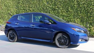 2024 Nissan Leaf SV in blue with a green hedge in the background.