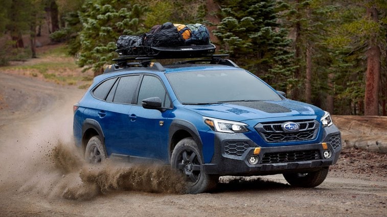 2024 Subaru Outback driving on a dirt road.