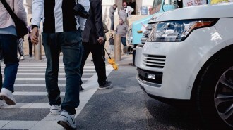 Pedestrians walk in front of an SUV