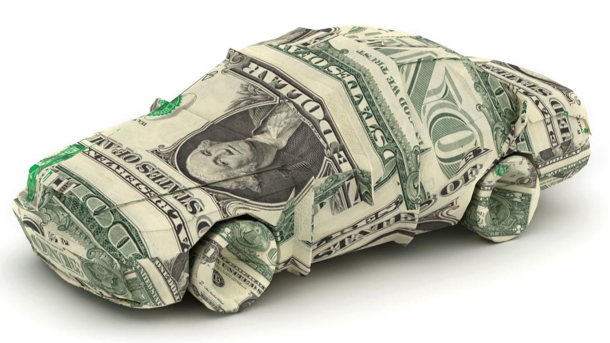 A toy car wrapped in dollar bills