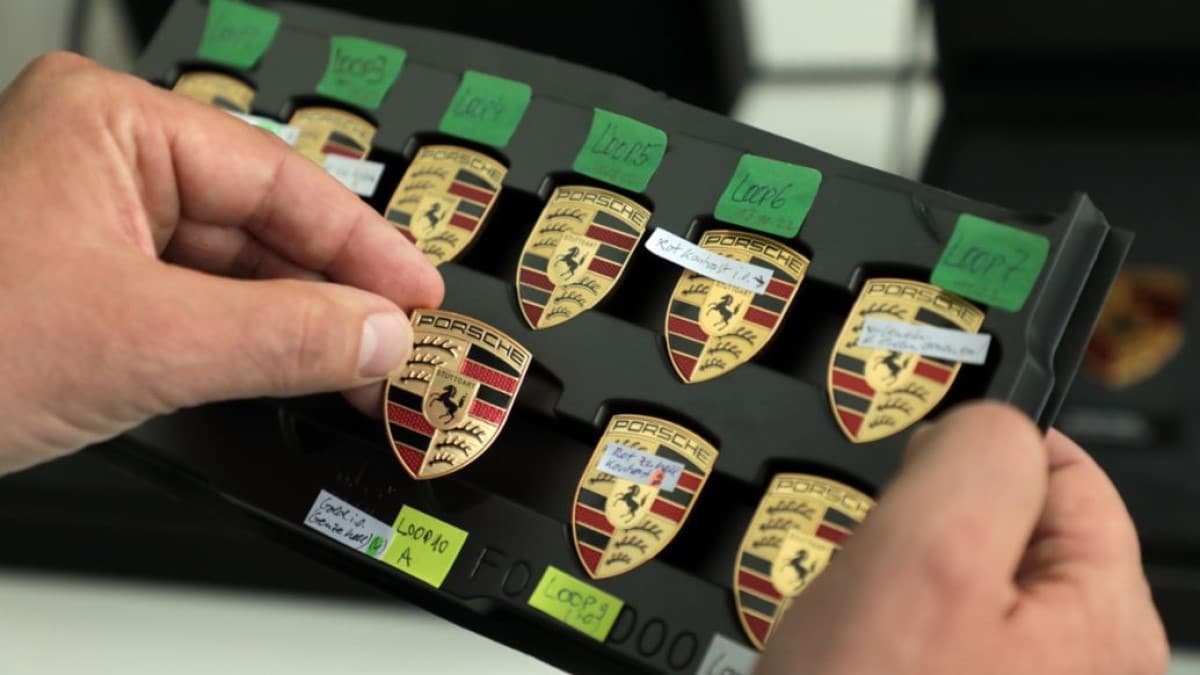 A Porsche artisan holds a selection of emblems