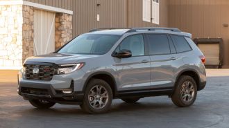 2024 Honda Passport TrailSport in grey near a barn.