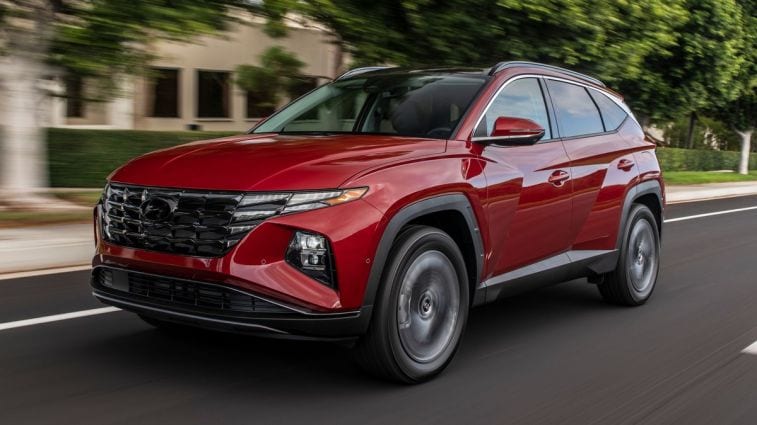 A red 2024 Hyundai Tucson driving down the street.