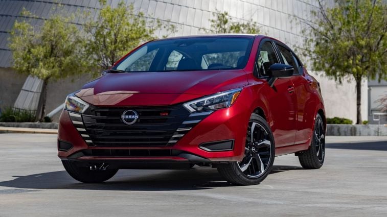 2024 Nissan Versa in red with trees in the background.