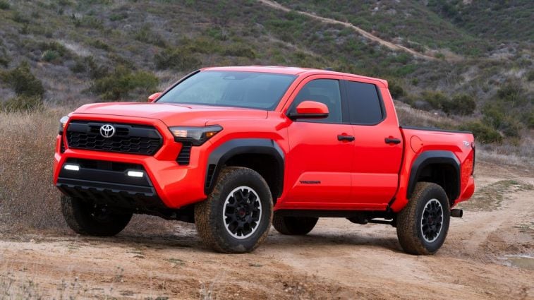 2024 Toyota Tacoma in orange on a dirt road.