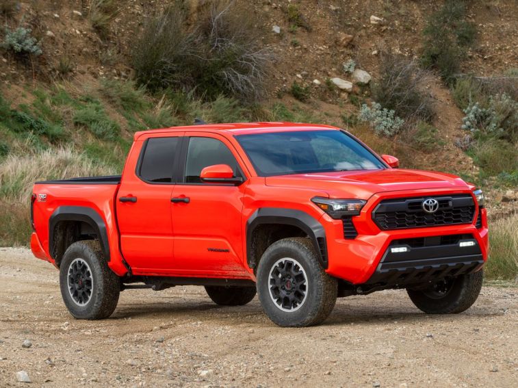 2024 Toyota Tacoma in orange on a dirt road.