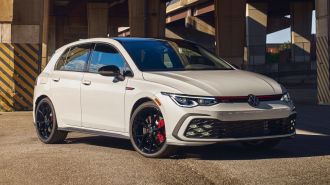 2024 Volkswagen Golf GTI in white under a freeway overpass.