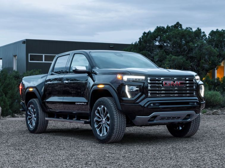 2023 GMC Canyon Denali parked on gravel with a house in the background.