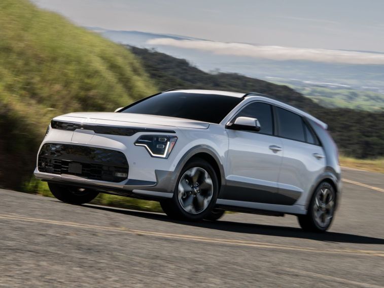 2023 Kia Niro EV in white driving up a road.