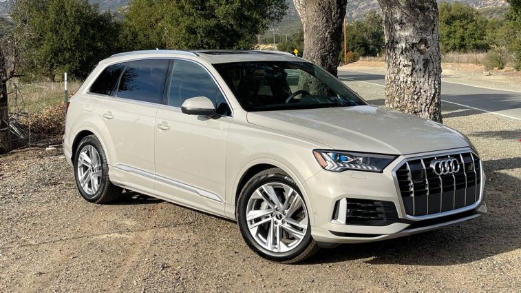 2024 Audi Q7 Prestige in Vicuna Beige Metallic parked next to a pair of trees.