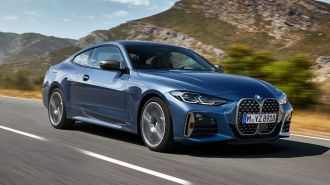 2024 BMW 4 Series in blue driving with hills in the background.