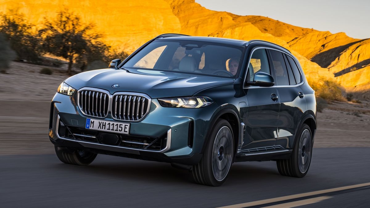2024 BMW X5 xDrive50e driving down a road.
