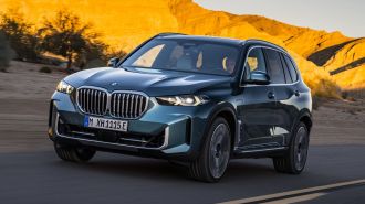 2024 BMW X5 xDrive50e driving down a road.