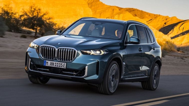 2024 BMW X5 xDrive50e driving down a road.