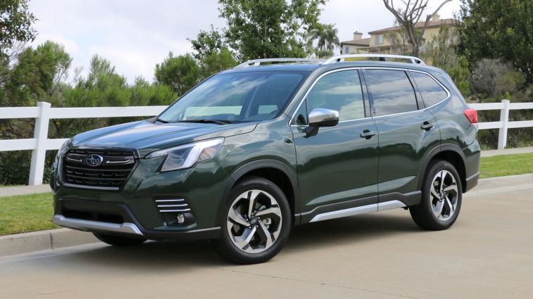 2024 Subaru Forester in green next to a white fence.