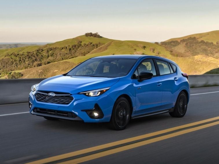 2024 Subaru Impreza RS in blue driving down a highway.