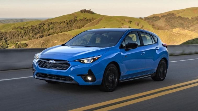2024 Subaru Impreza RS in blue driving down a highway.