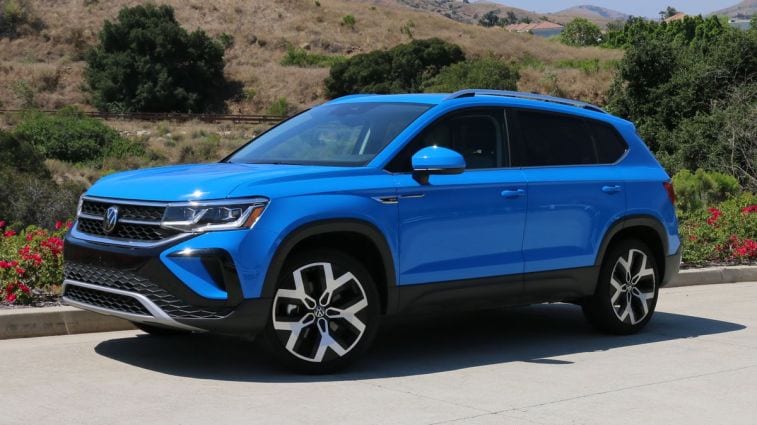 2024 Volkswagen Taos in blue with shrubs in the background.