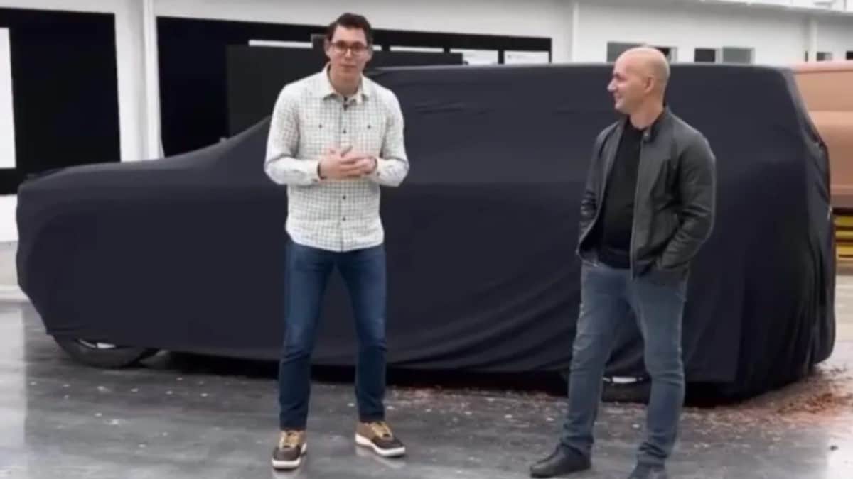 Rivian CEO RJ Scaringe and lead designer Jeff Hammoud stand in front of a design buck of the upcoming Rivian R2 SUV