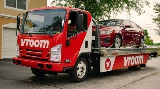 A Vroom truck delivering a sedan