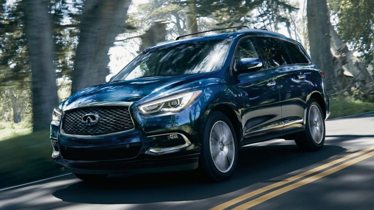2020 Infiniti QX60 in blue driving down a road with trees.