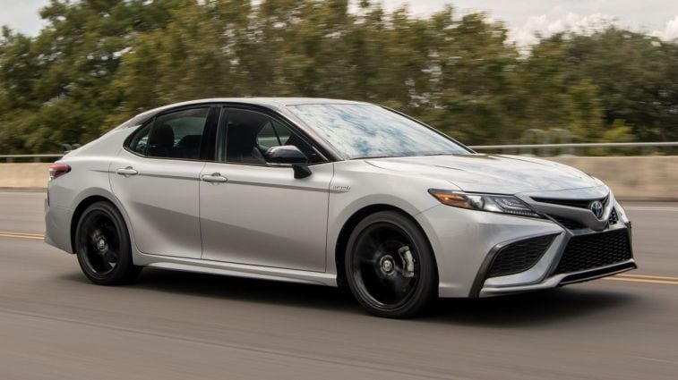 2021 Toyota Camry Hybrid driving down a highway.