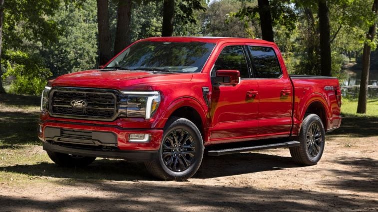 2024 Ford F-150 Lariat in red with trees in the background.