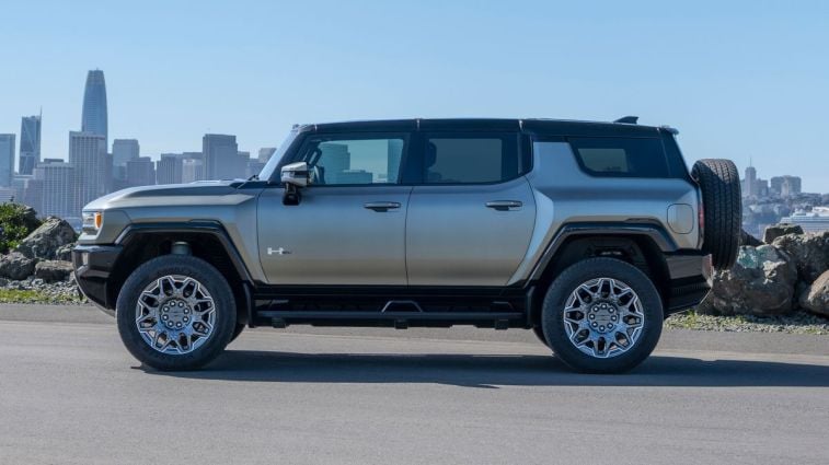 2024 GMC HUMMER EV SUV in Moonshot Green Matte parked in front of the San Francisco skyline.