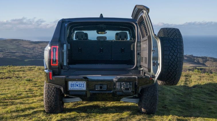 2024 GMC HUMMER EV SUV with open swing-gate in grassy off-road location.