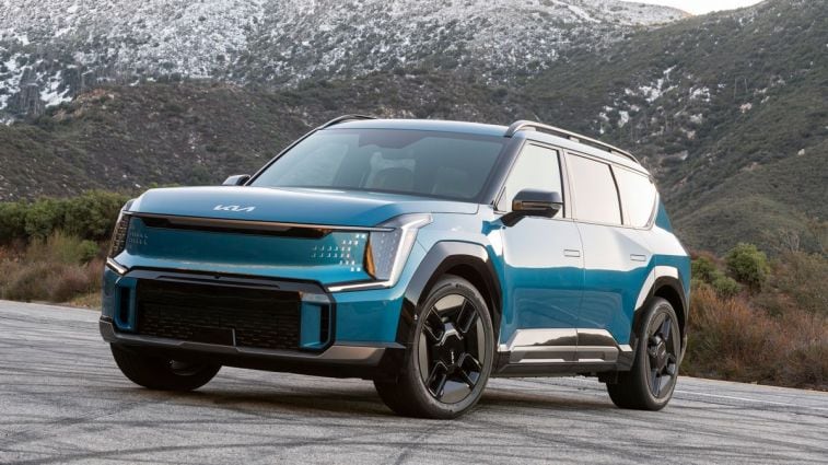 2024 Kia EV9 in blue with snow dusted mountains in the background.